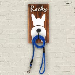 ξύλινη κρεμάστρα με σχέδιο σκυλάκι και σιδερένιο γάντζο με κρεμασμένο λουρί σκύλου πάνω σε τοίχο