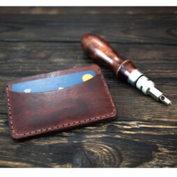 δερμάτινο πορτοφόλι λεπτό με κάρτα στη μία θήκη πάνω σε σκούρα ξύλινη επιφάνεια