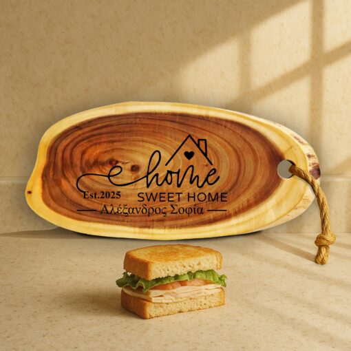 Προσωποποιημένο Ξύλο Σερβιρίσματος Φέτα Κορμού με Χάραξη "Home Sweet Home Est. 2025 - Αλέξανδρος Σοφία". Ρουστίκ ξύλινο πλατώ 52x23 με σάντουιτς σε πάγκο κουζίνας.
