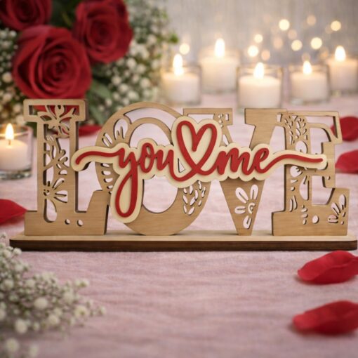 Ξύλινο επιτραπέζιο διακοσμητικό με τη λέξη "LOVE" σε φυσικό χρώμα ξύλου και περίτεχνα σκαλίσματα, που φέρει στο κέντρο την κόκκινη επιγραφή "You & Me" με μια καρδιά, τοποθετημένο σε ρομαντικό φόντο με τριαντάφυλλα και κεριά.