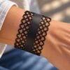 Black leather cuff bracelet for women with an intricate laser-cut playing card suit design featuring clubs, diamonds, spades and hearts. A wide statement bracelet with a distinctive geometric pattern and elegant black finish.